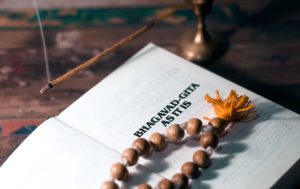 Opened Bhagavad Gita and rosary lying on a wooden table.